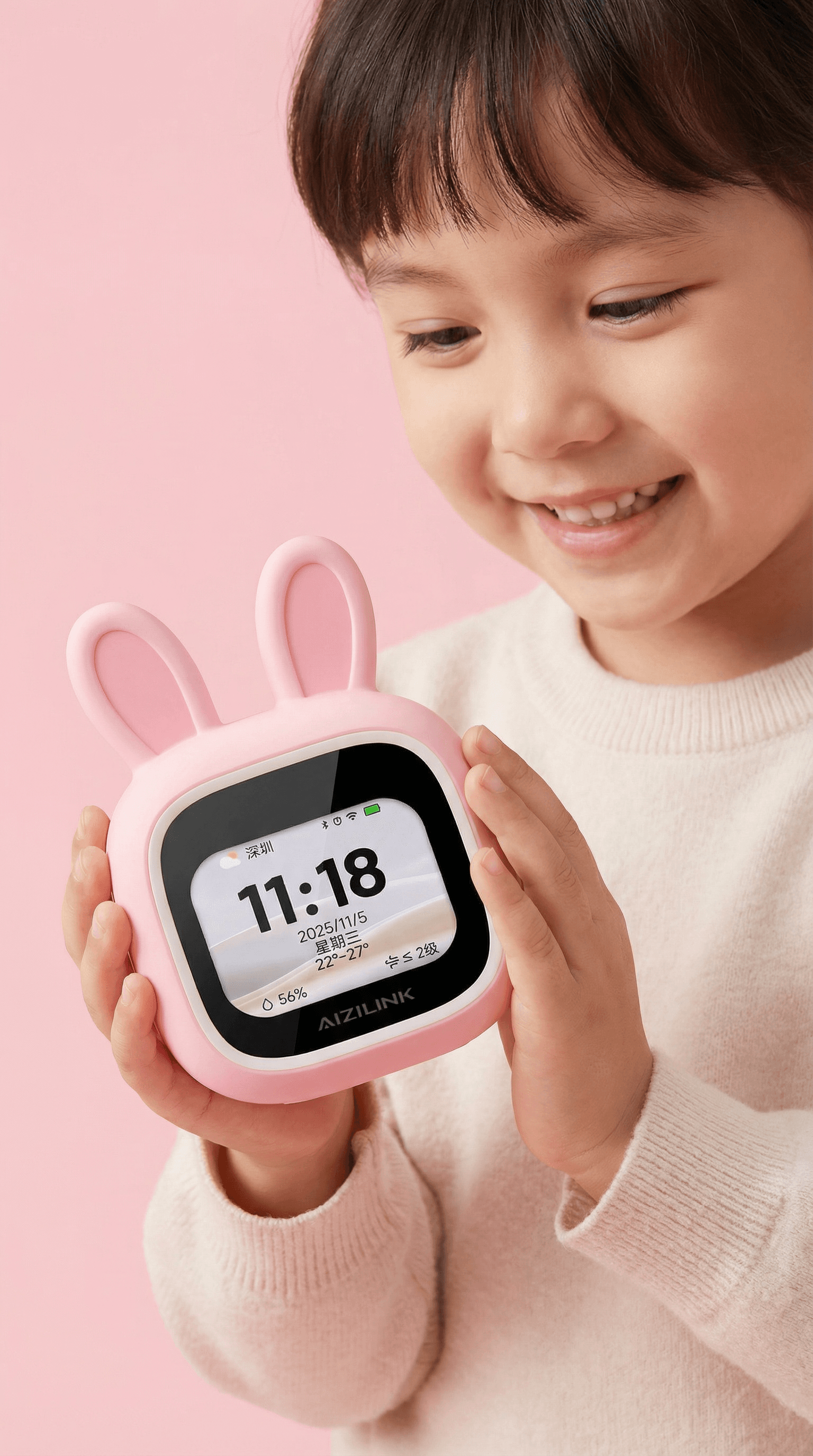 Child presenting a pink bunny smart clock in a clean pink studio portrait