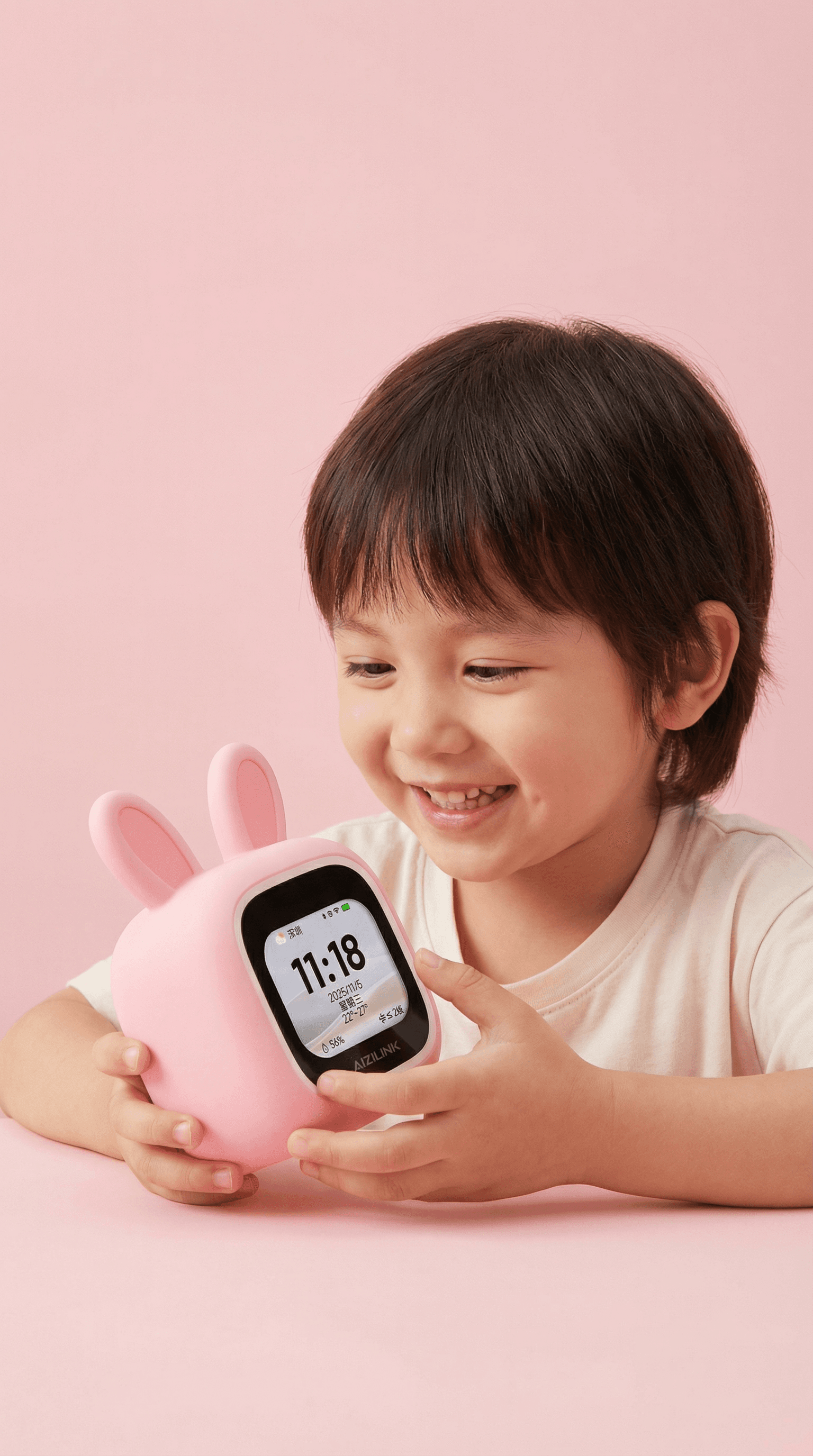 Child using a pink bunny-shaped smart clock in a soft pink studio setting